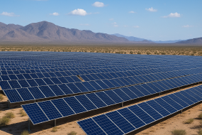 A vast desert solar farm with rows of solar panels under a bright blue sky, representing utility-scale solar energy projects.